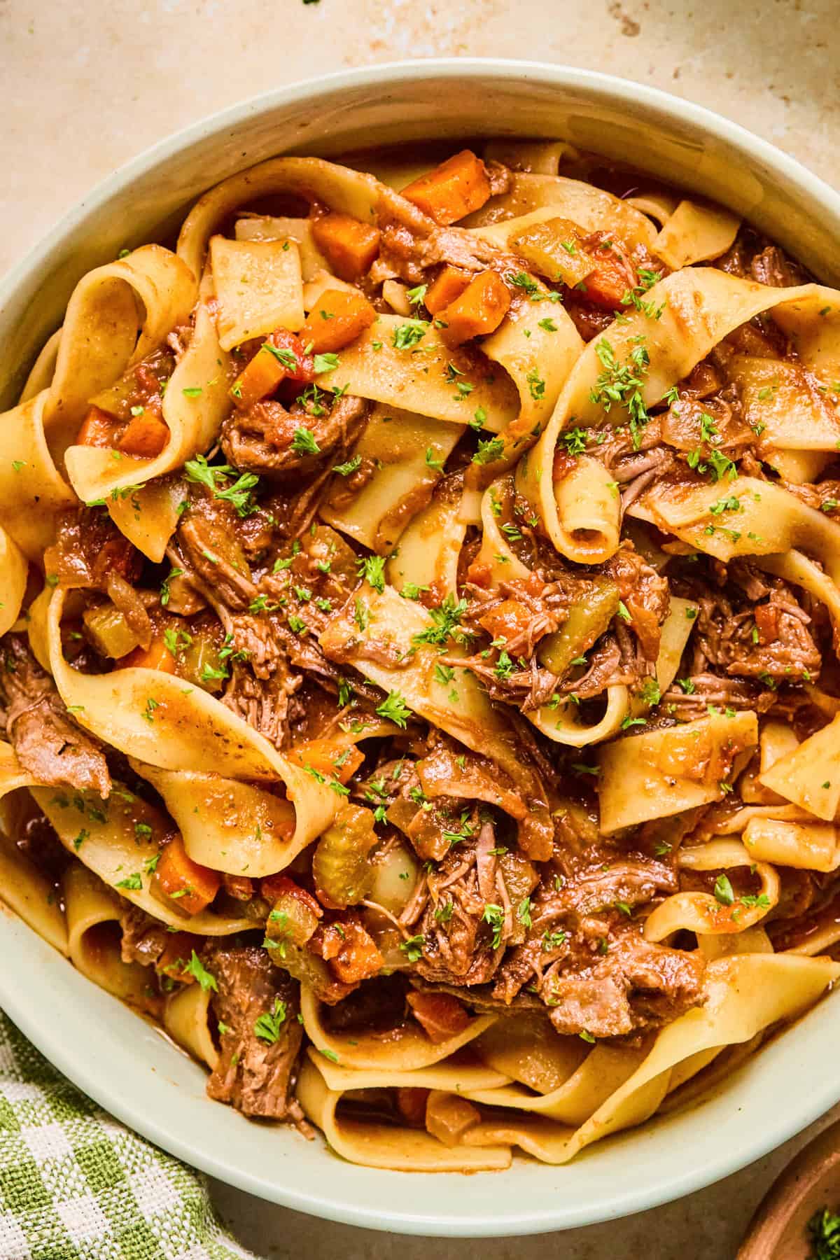 Short rib ragu tossed with pappardelle pasta and topped with chopped parsley