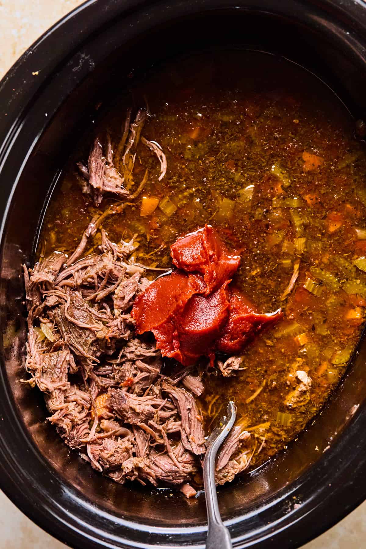 Shredded meat and tomato paste added to crockpot.
