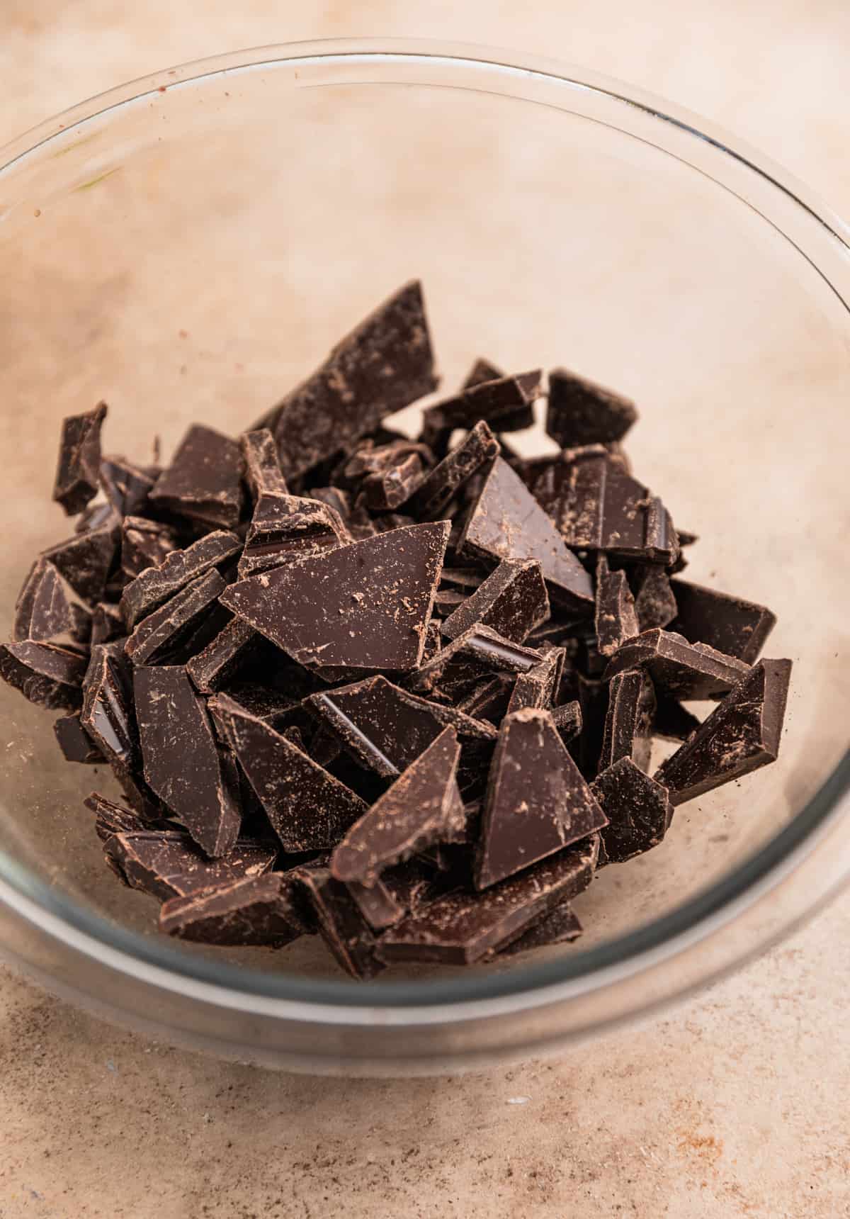 Chopped dark chocolate in glass bowl.
