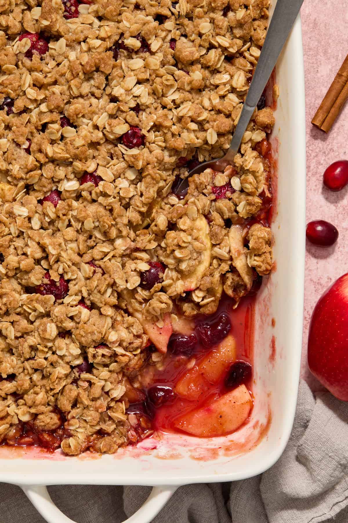 Spoon scooping into dish with baked apple cranberry crisp.