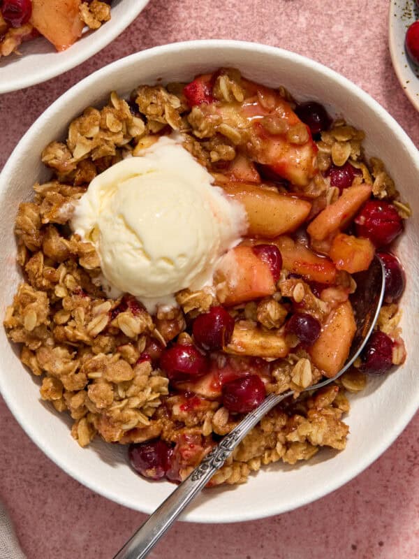 Bowl with cranapple crisp with vanilla ice cream and spoon propped in the bowl.