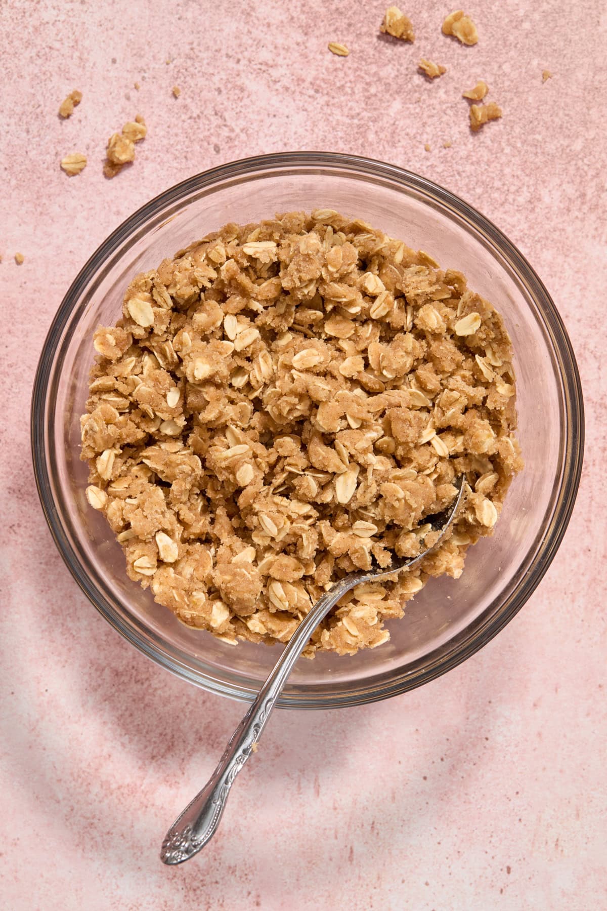 Oat crisp topping mixture in bowl with spoon.