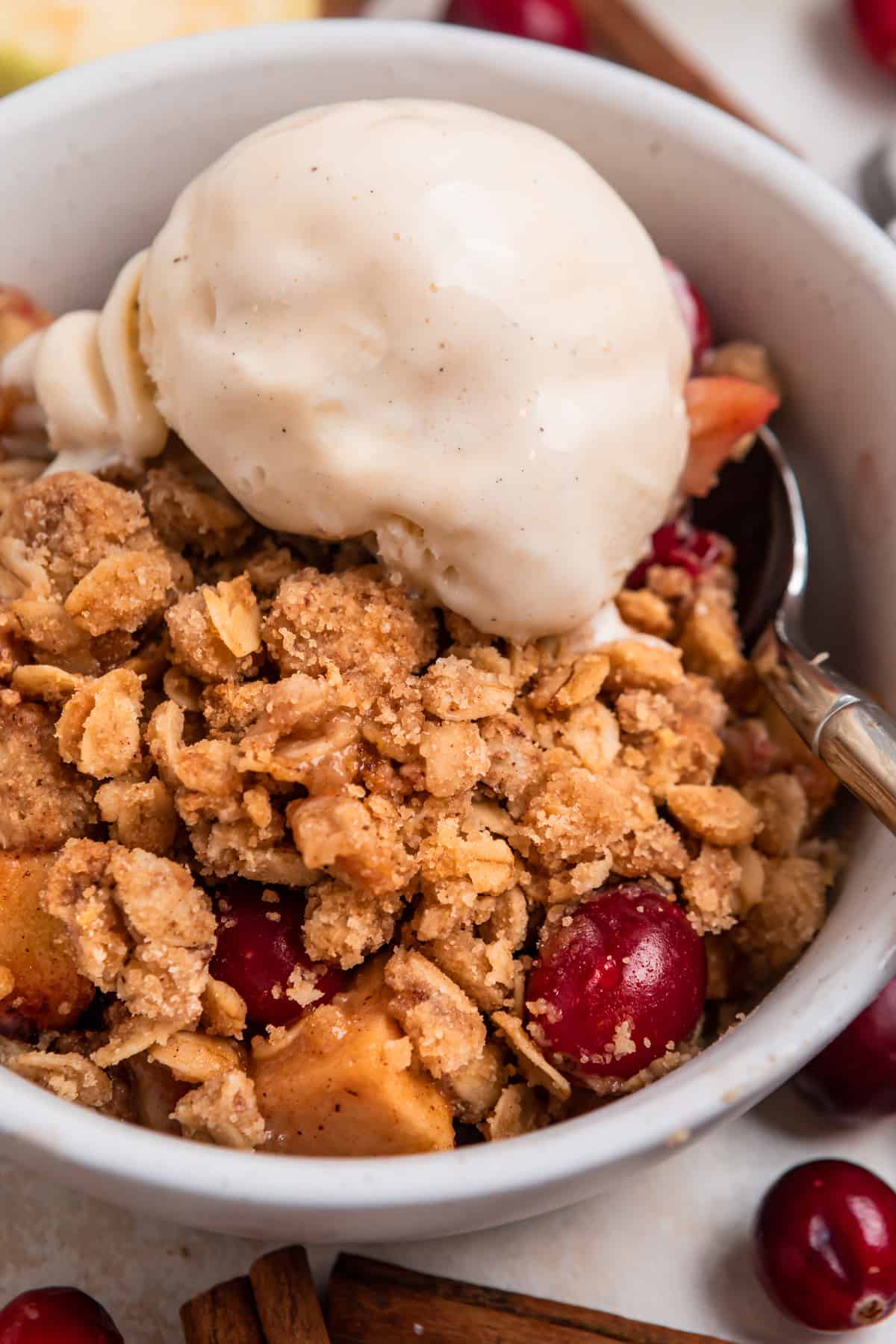 Cranberry Apple crisp with vanilla ice cream scooped on top and spoon.