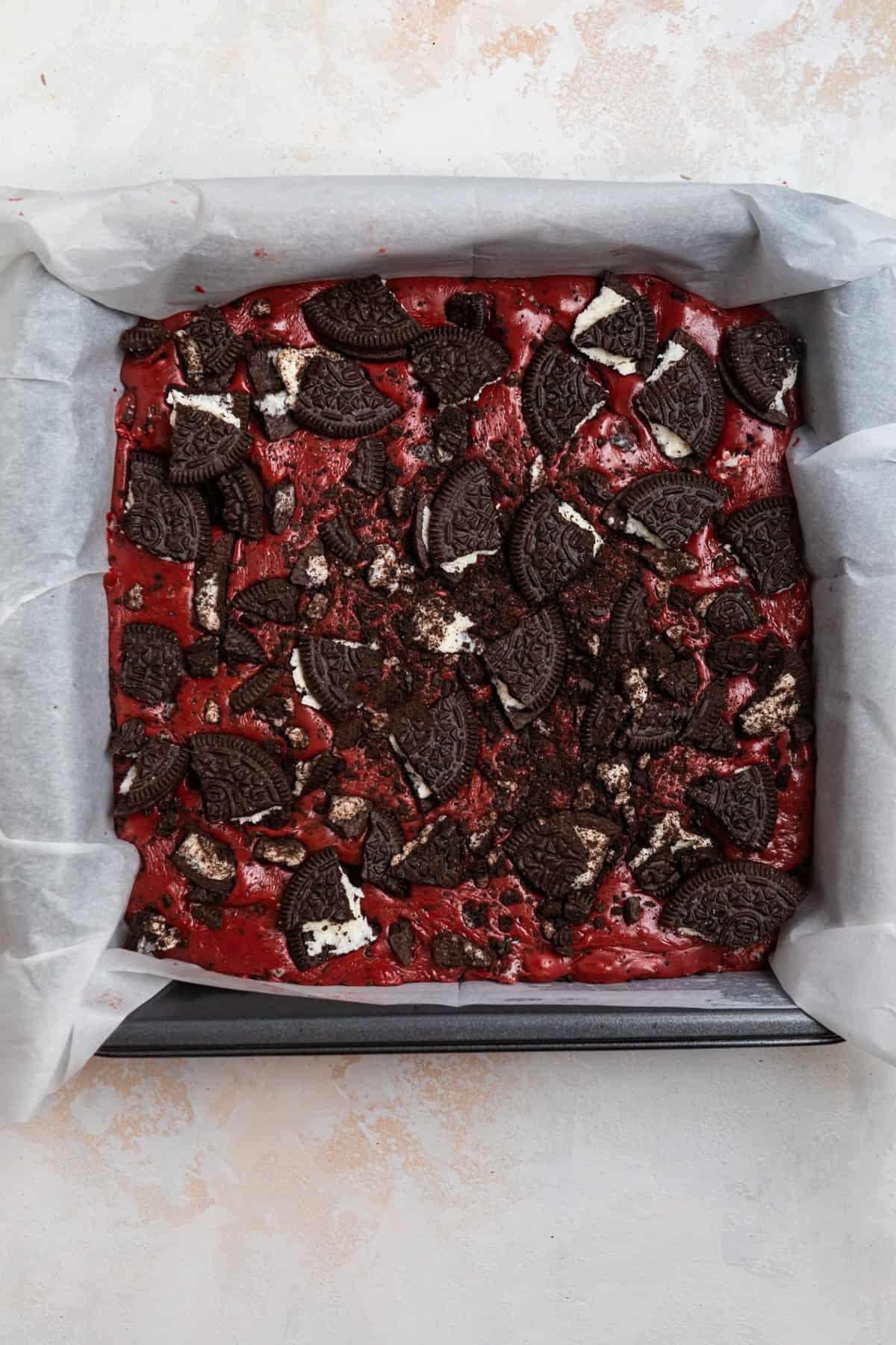 Prepared fudge in parchment lined baking pan and topped with crushed up Oreos.