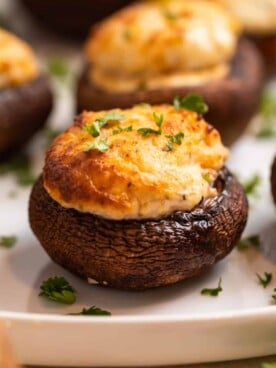 Air fried stuffed mushrooms on white plate topped with chopped parsley.