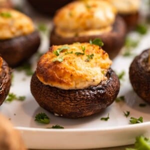 Air fried stuffed mushrooms on white plate topped with chopped parsley.