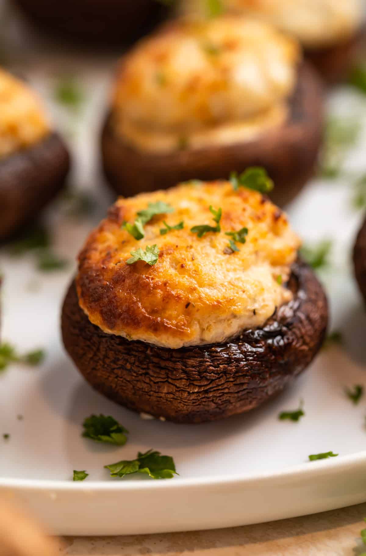 Air fryer stuffed mushrooms on white plate topped with chopped parsley.