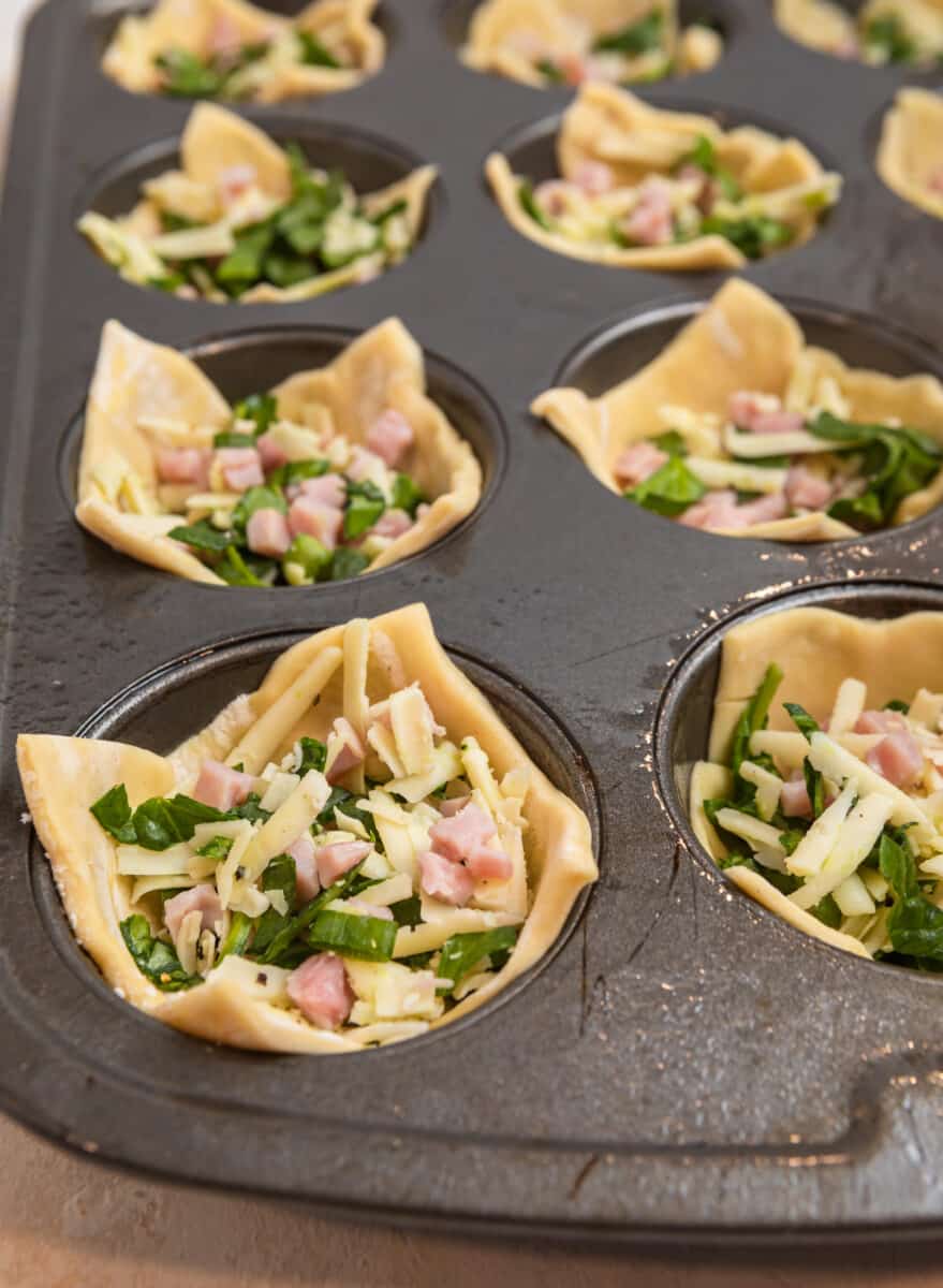 Puff pastry muffin cups filled with ham, cheese and spinach mixture.
