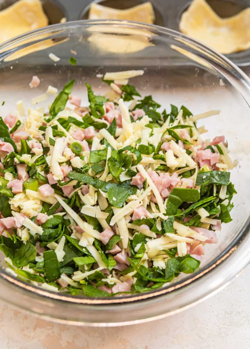 Ham, cheese and spinach mixture in glass mixing bowl.