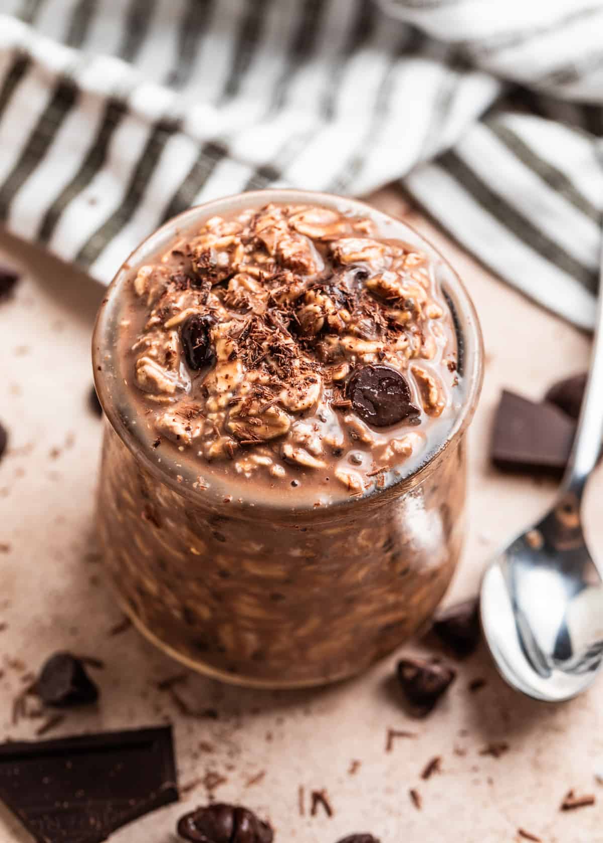 Chocolate overnight oats in glass jar topped with chocolate chips and chocolate shavings.