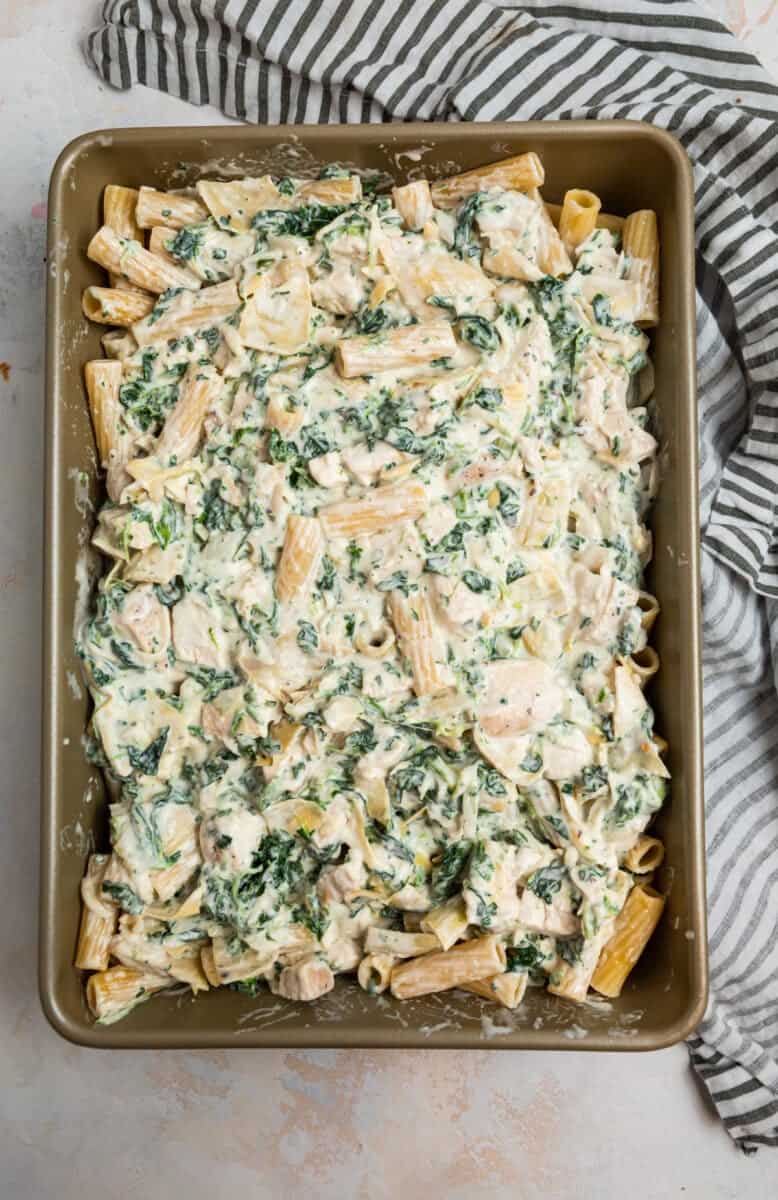 Pan with chicken, spinach and artichoke casserole before baking.