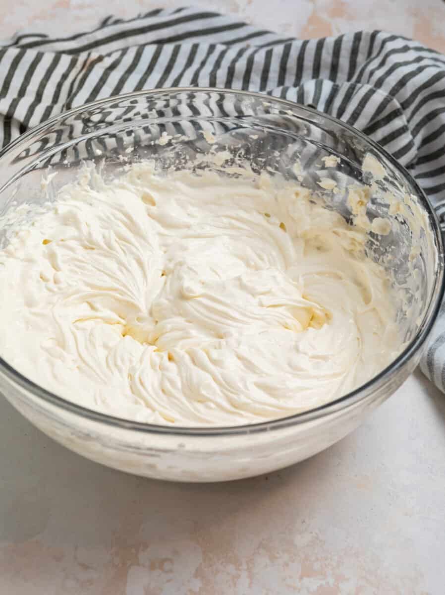 Cream cheese and cream mixed in glass mixing bowl.