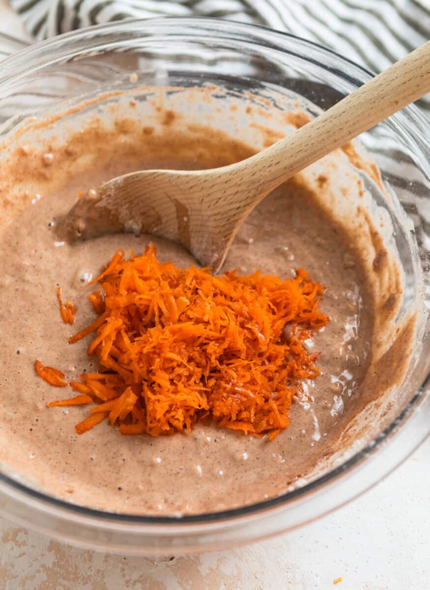 Shredded carrots in mixing bowl with carrot cake donut mixture.