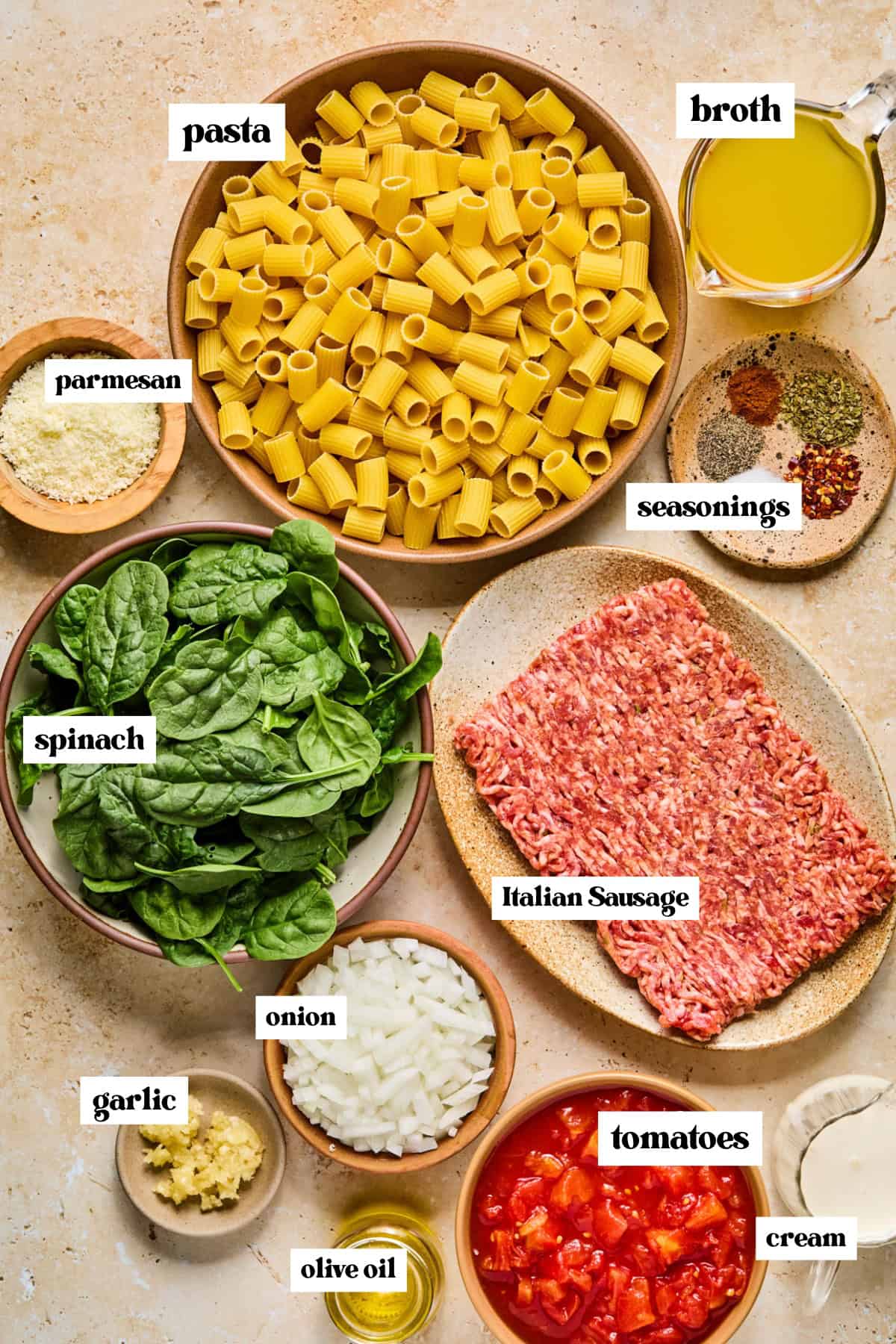 Pasta, Italian sausage, cream, parmesan, and other labeled ingredients on surface.