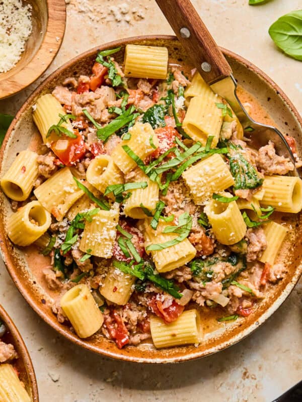 Bowl with pasta and fork topped with basil and cheese.