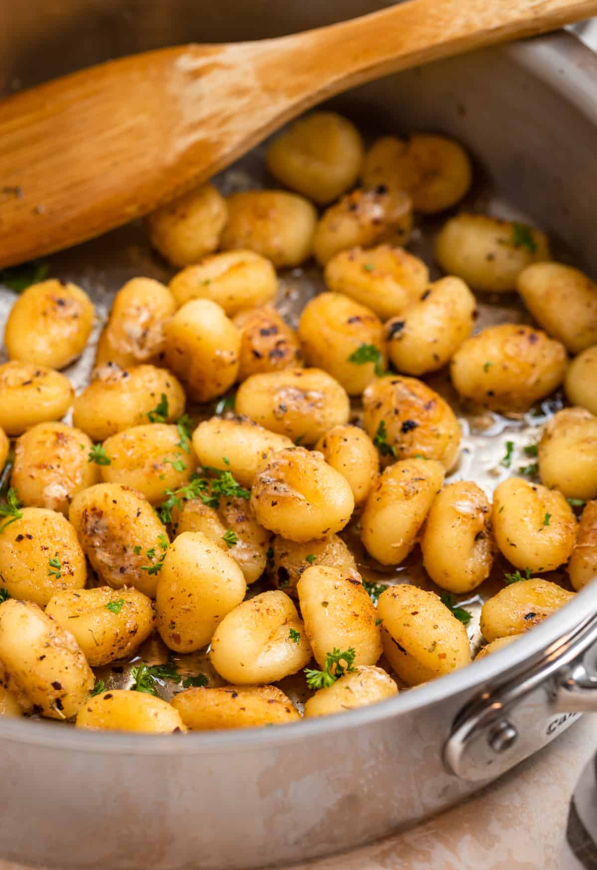 Gnocchi in skillet with parmesan, butter, chopped parsley.