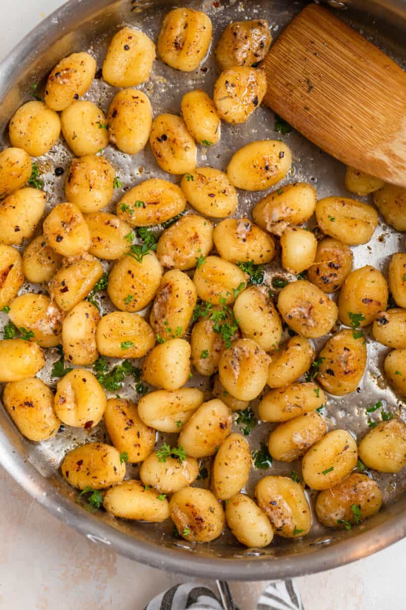 Gnocchi in skillet with parmesan, garlic and chopped parsley.