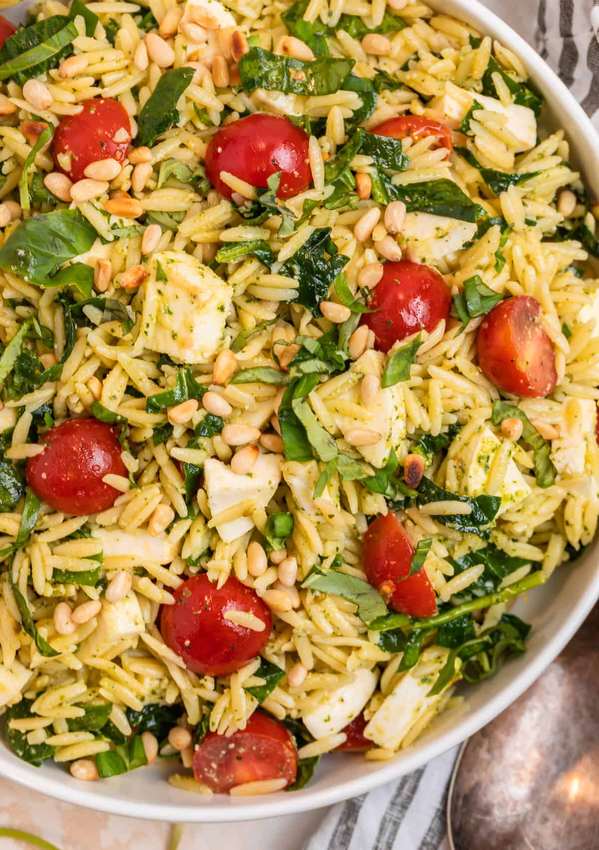 White serving bowl with orzo salad with pesto.