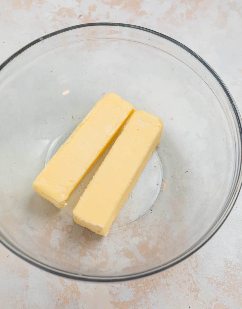 Two sticks of butter in glass mixing bowl.