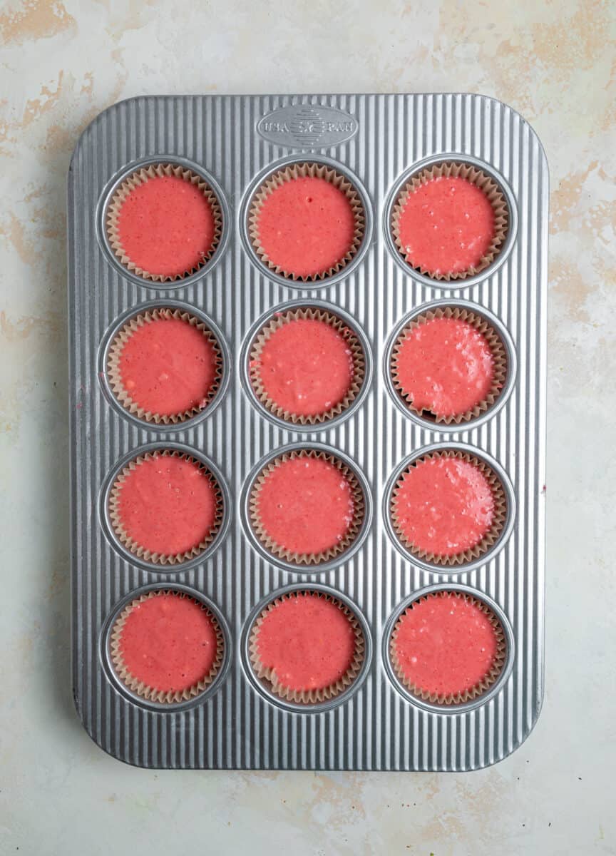 Cupcake tin with strawberry cake batter in each muffin cup.