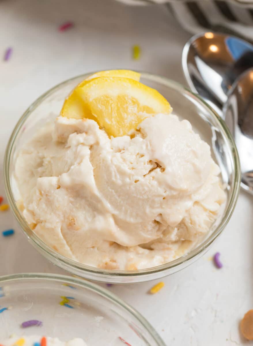 Lemon cheesecake protein ice cream in glass bowl with lemon slices.