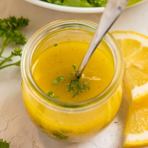 Lemon dijon dressing in glass jar with spoon.
