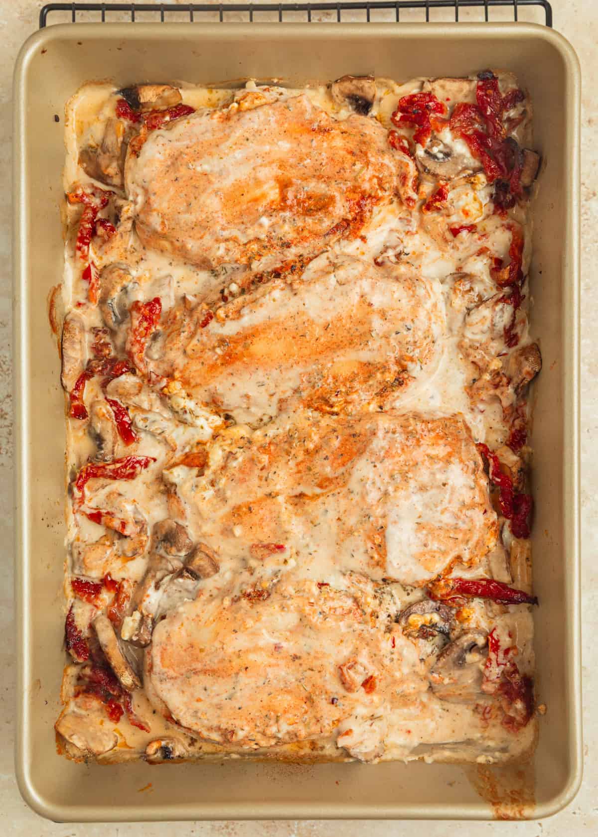 Baked tuscan chicken in pan with creamy sauce over top.