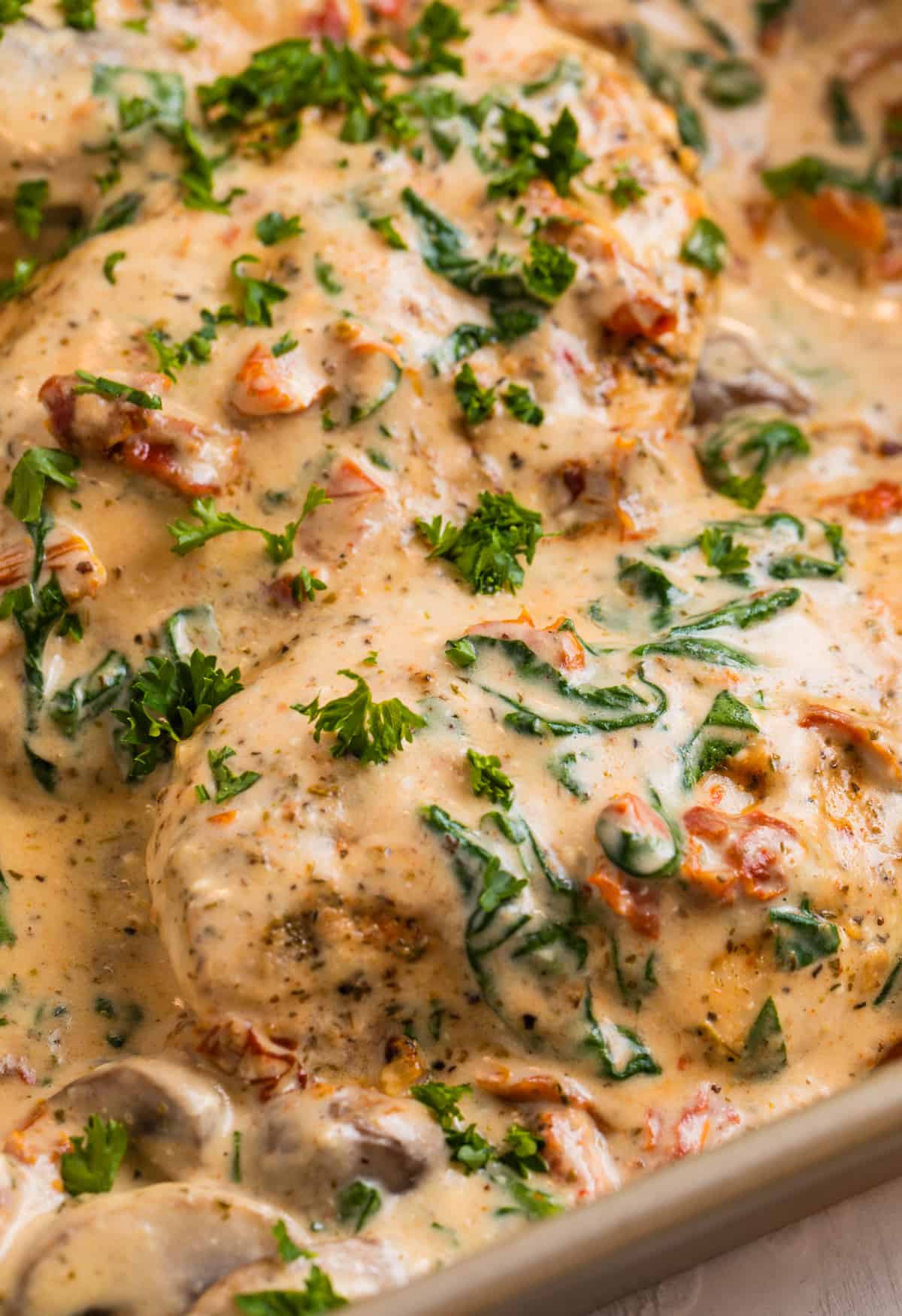 Baked creamy tuscan chicken in pan topped with fresh parsley.