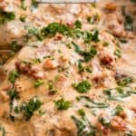 Baking pan with creamy baked Tuscan chicken topped with freshly chopped parsley.