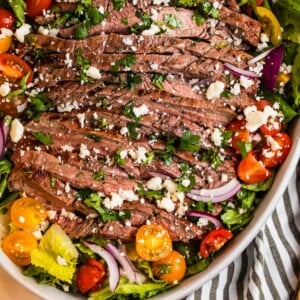 Grilled flank steak salad in dish topped with freshly chopped cilantro and cheese.