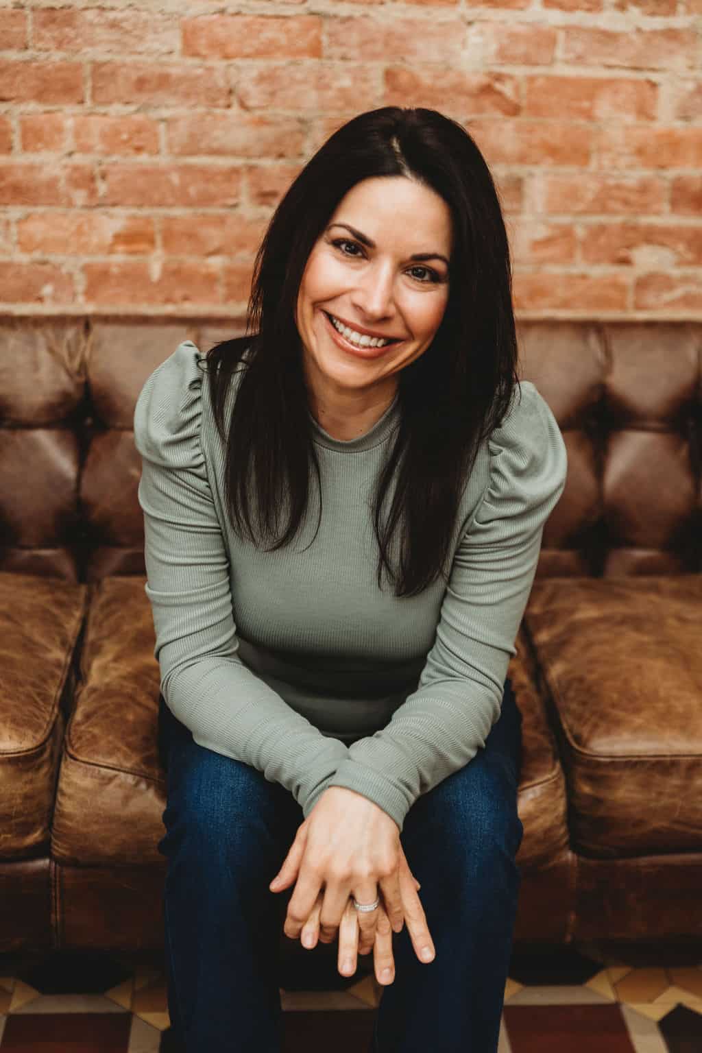 Lorie Yarro seated on couch with arms folded.