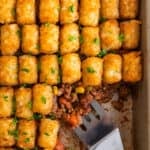 Pan with tater tot shepherds pie with serving utensil scooping in.