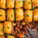 Spatula scooping into pan with tater tot shepherd's pie topped with chopped parsley.