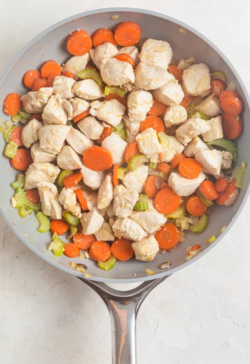 Diced chicken cooked in skillet with carrots, celery and onion.
