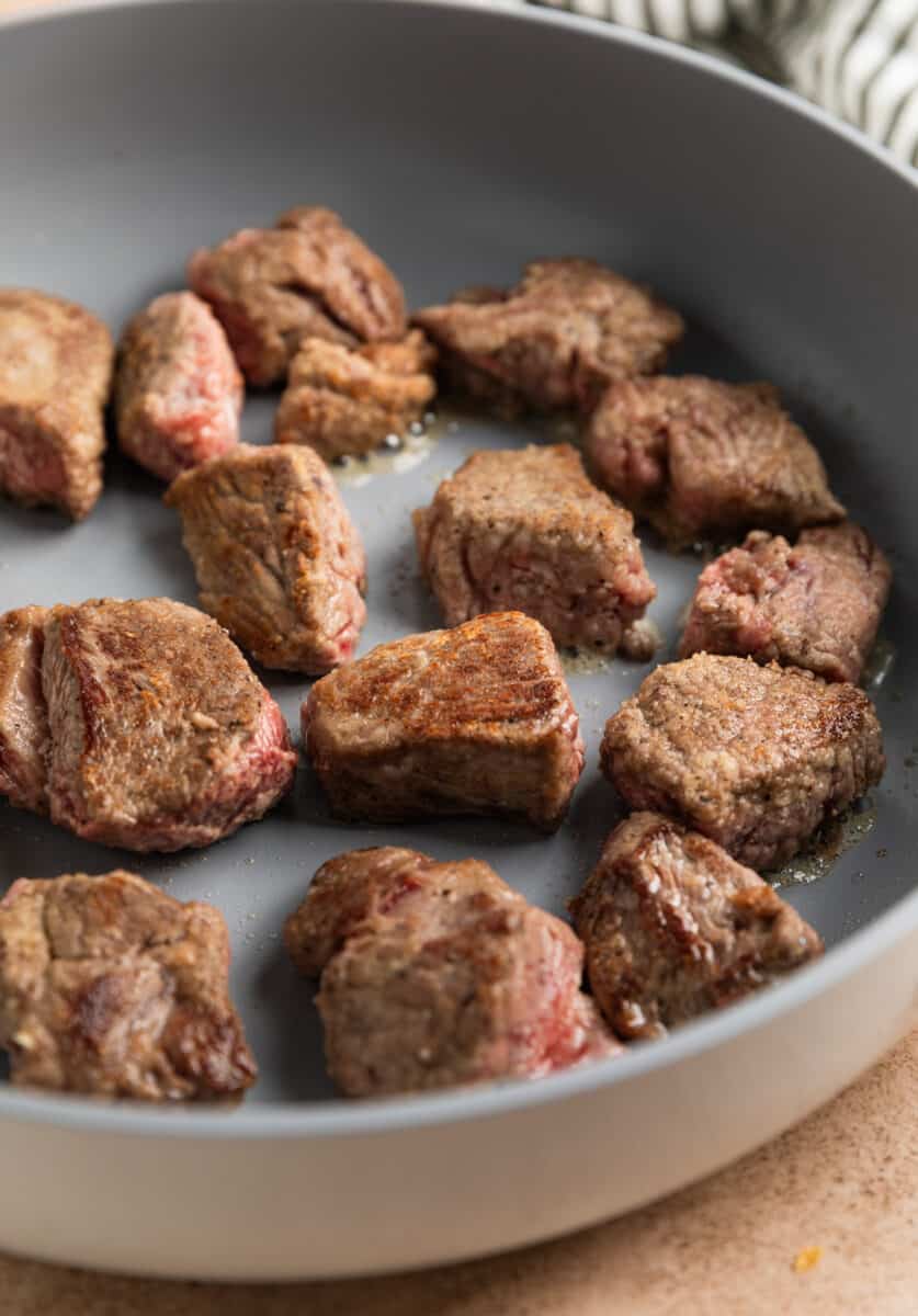 Seared cubed beef stew in skillet.