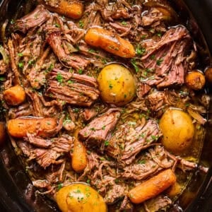 Crockpot with prepared chuck roast and vegetables.