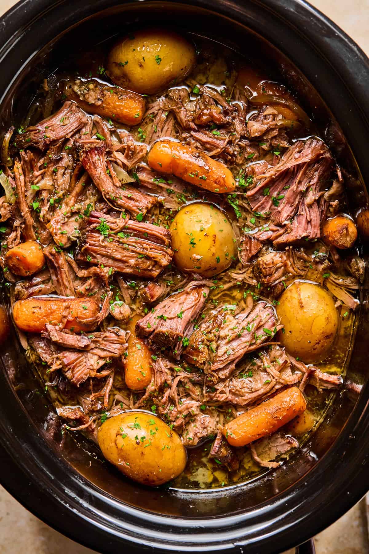 Crockpot with prepared chuck roast and vegetables.