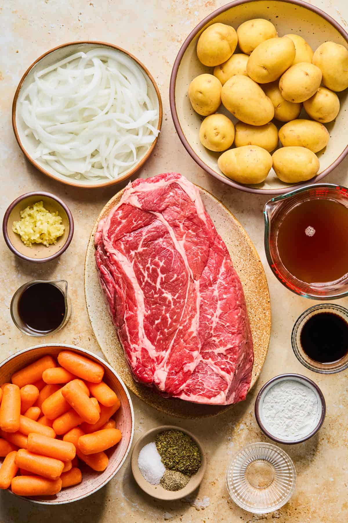 Chuck roast, potatoes, carrots, onion and other ingredients needed for recipe.