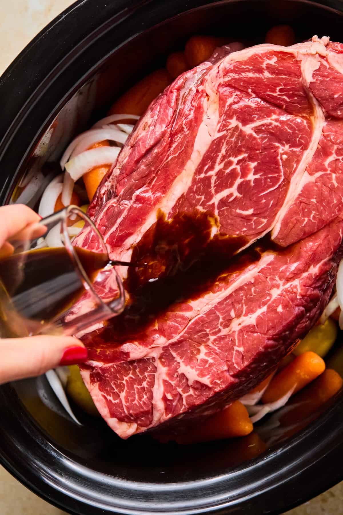 Chuck roast on top of vegetables in crock pot before cooking.
