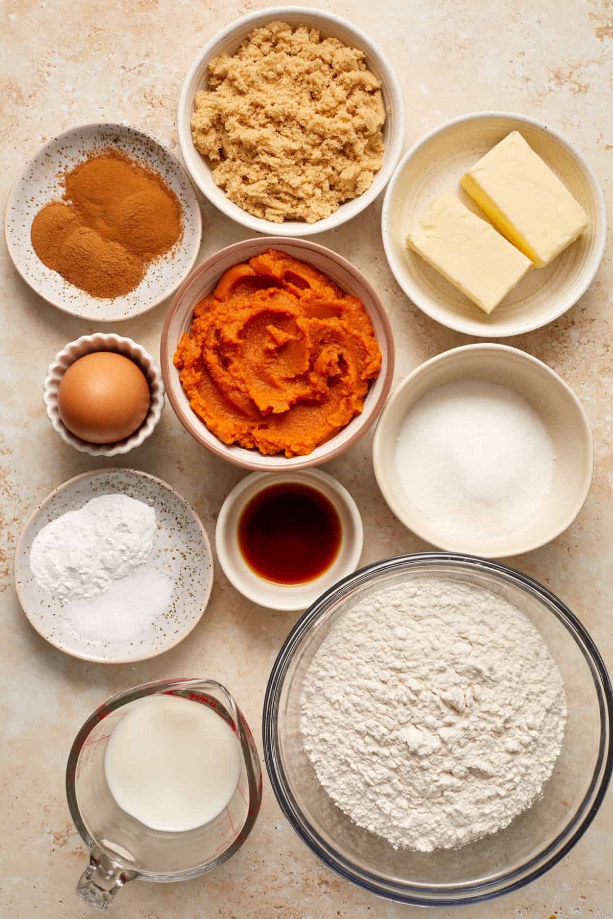 Brown sugar, flour, pumpkin, egg and other ingredients arranged on surface to make recipe.