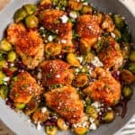 Overhead view of pan with cooked chicken thighs and brussel sprouts topped with goat cheese.