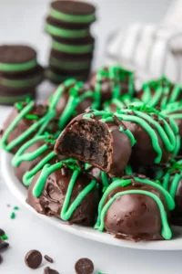 Mint chocolate truffles coated in chocolate and green drizzle over top.