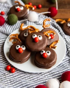 White plate with chocolate covered Oreos with reindeer nose and pretzel antlers.