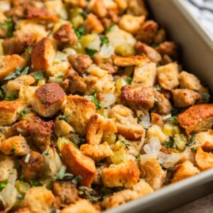 Turkey sausage sourdough bread stuffing in pan with fresh herbs on top.