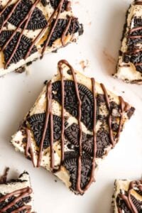 Oreo cheesecake bars sliced on counter and drizzled with chocolate.