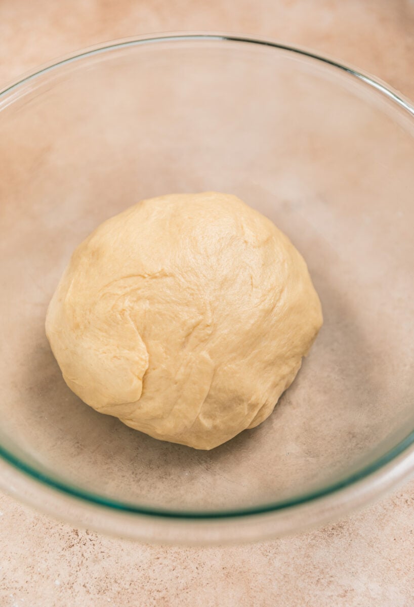 Buttermilk cinnamon roll dough ball in glass bowl before rising.