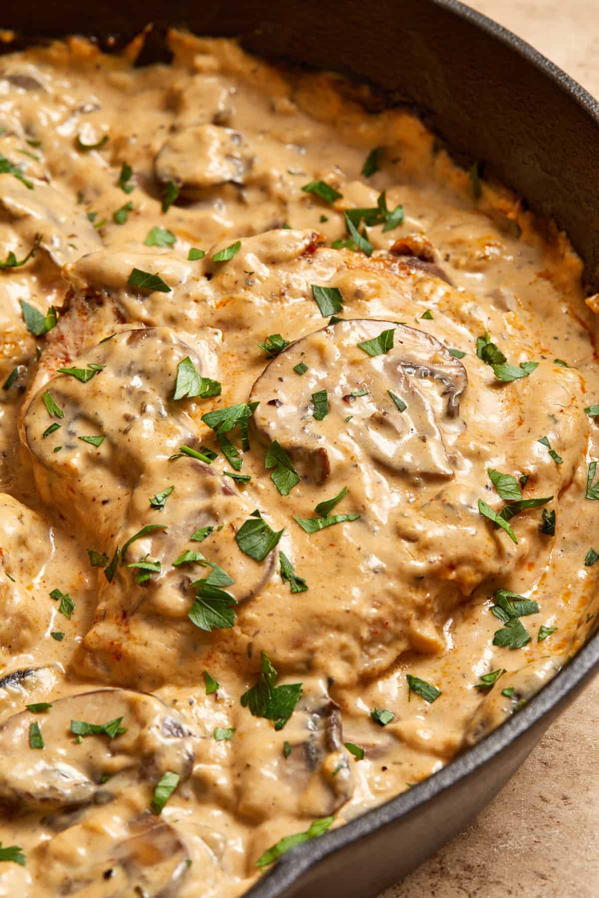 Skillet with cream of mushroom pork chops with parsley on top.