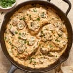 Skillet with cream of mushroom pork chops topped with chopped parsley.