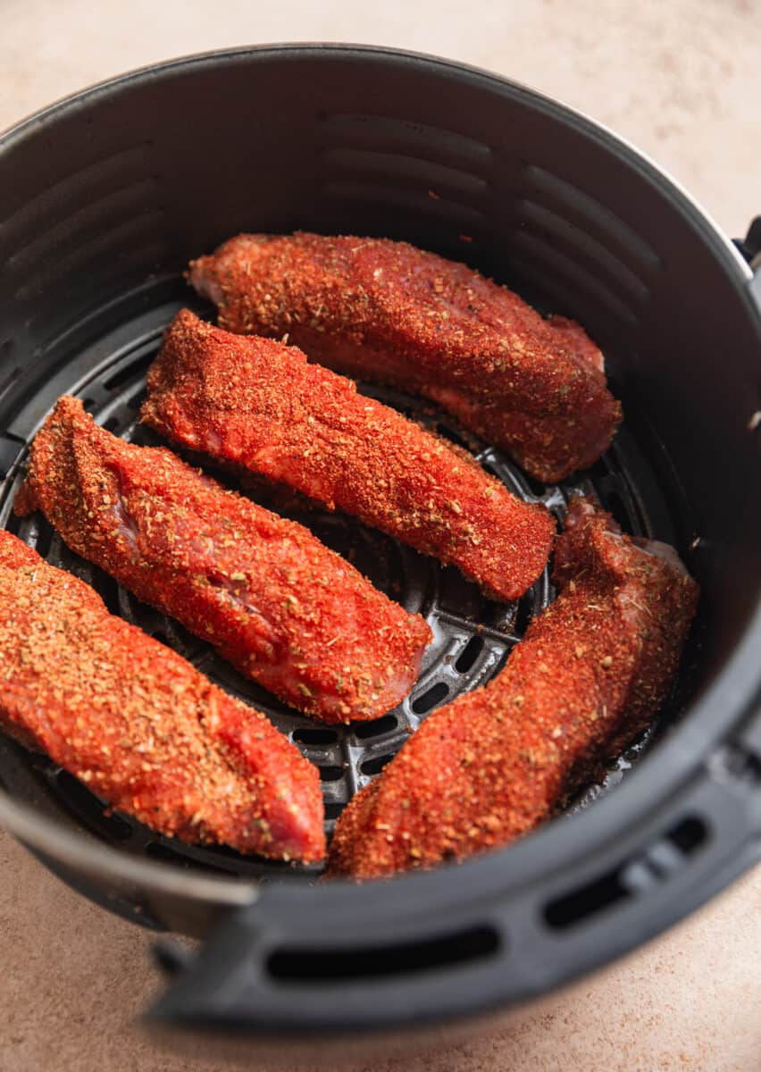 Country style ribs with dry rub in oiled air fryer basket.