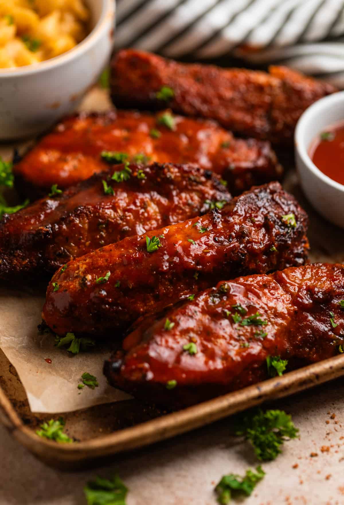 Air fryer country style ribs with BBQ sauce on parchment lined tray.